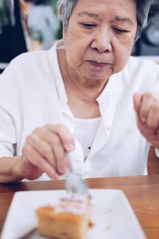 old asian elderly senior elder woman eating cake at restaurant.