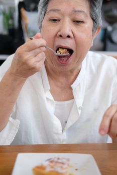 old asian elderly senior elder woman eating cake at restaurant.