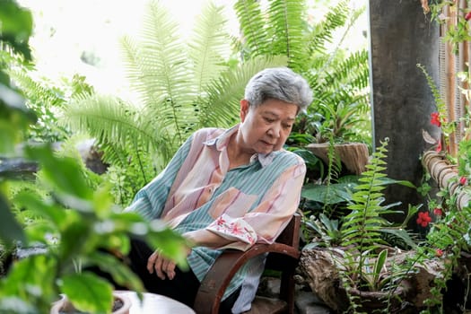 elder woman resting in garden. elderly female relaxing outdoors. senior leisure lifestyle