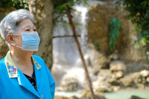 asian old elderly elder woman wearing facial mask resting relaxing in garden. senior leisure lifestyle