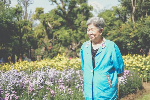 asian old elderly elder woman resting relaxing in flower garden. senior leisure lifestyle