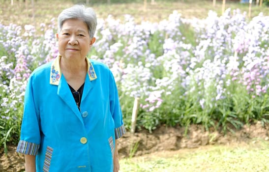 asian old elderly elder woman resting relaxing in flower garden. senior leisure lifestyle