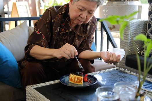 old asian elderly senior elder woman eating cheesecake at home