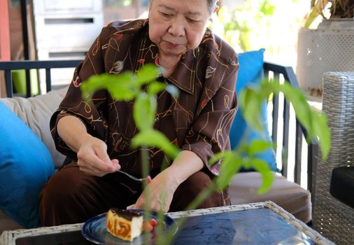 old asian elderly senior elder woman eating cheesecake at home