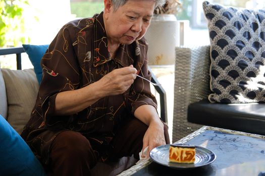 old asian elderly senior elder woman eating cheesecake at home