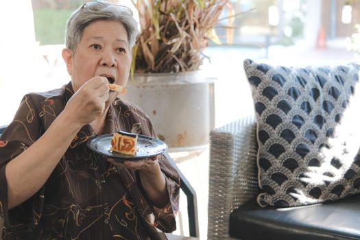 old asian elderly senior elder woman eating cheesecake at home