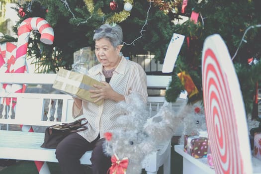 asian old elder woman elderly senior holding gift present box near christmas tree