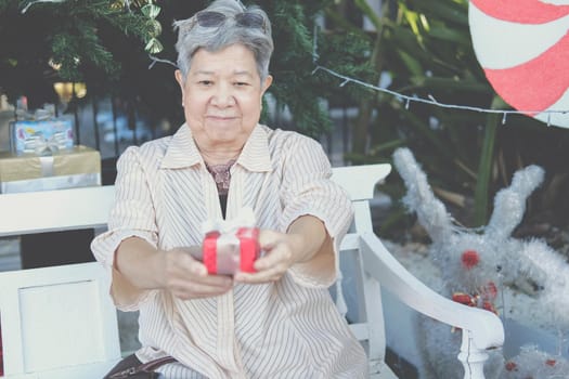 asian old elder woman elderly senior holding gift present box near christmas tree