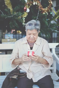 asian old elder woman elderly senior holding gift present box near christmas tree