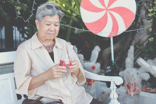 asian old elder woman elderly senior holding gift present box near christmas tree