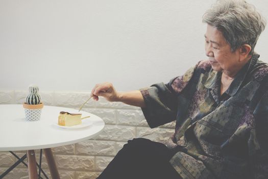 old asian elderly senior elder woman eating cheesecake at restaurant. mature retirement lifestyle