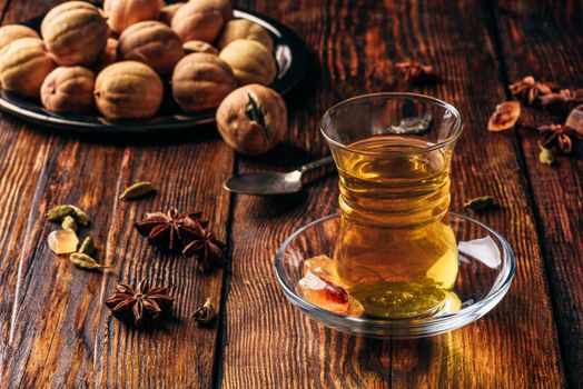 Oriental tea with star anise, cardamom and dried lime in armudu glass over wooden surface