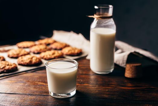 Glass of Milk with Bottle and Oatmeal Cookies on Parchment Paper.