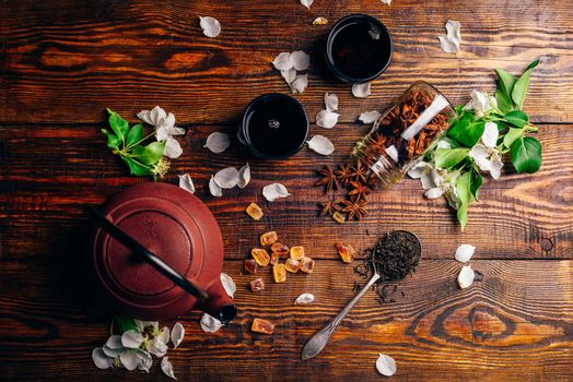 Teapot with Spoonful of Tea, Apple Flowers, Sugar and Anise Star on Wooden Table. View from Above.