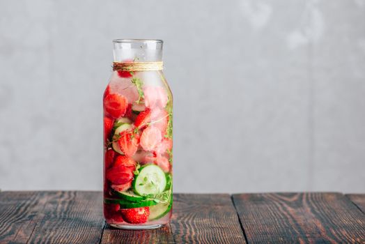 Bottle of Infused Water with Fresh Strawberry, Sliced Cucumber and Springs of Thyme. Copy Space.