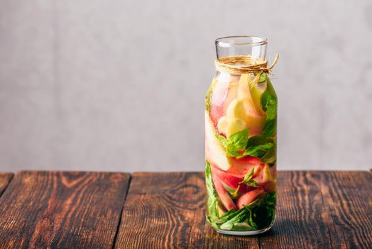 Bottle of Water Infused with Sliced Peach and Basil Leaves.