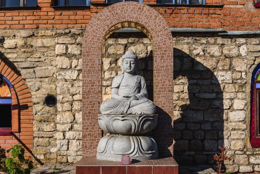 White stone statue of a Buddha on masonry background