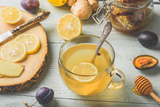 Cup of tea with lemon, honey and ginger over wooden surface