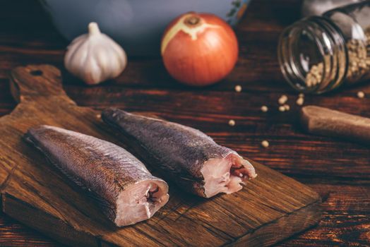 Hake carcasses on cutting board with spices and vegetables