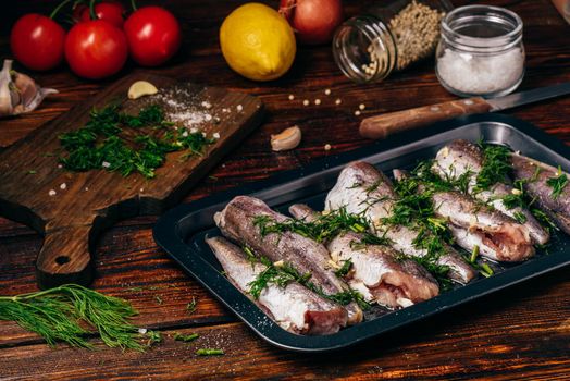 Hake carcasses on baking sheet with vegetables and spices