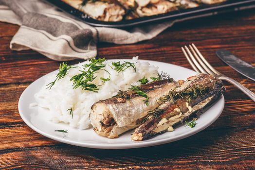 Baked hake carcasses with rice on white plate