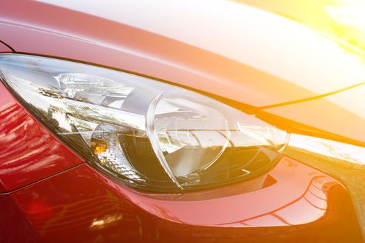 Closeup headlights of red car with sunlight