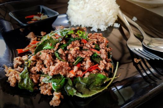 Stir fried chopped meat with chili and basil and  steamed rice on black plate