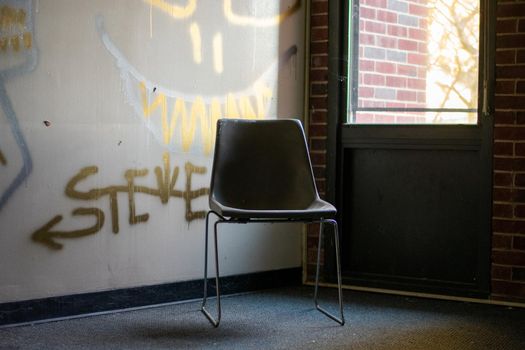 An Empty Chair Next to a Window in a Corner in an Abandoned Building