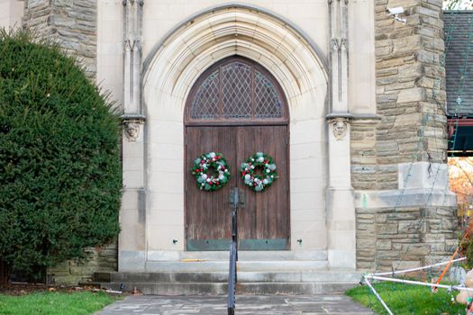 A Large Brown Wooden Door on a Church With Christmas Wreaths On Them