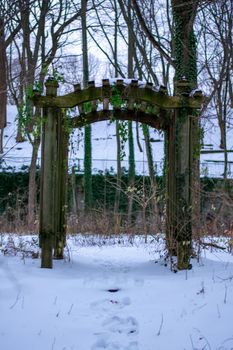 A Wooden Garden Arch in a Forest Covered in Snow
