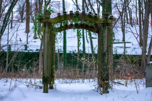 A Wooden Garden Arch in a Forest Covered in Snow
