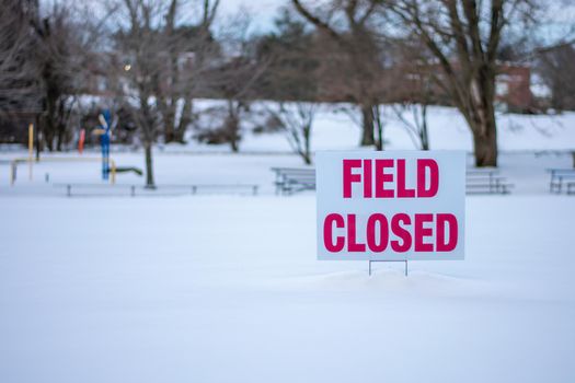 A Sign That Says Field Closed in a Snow Covered Clearing