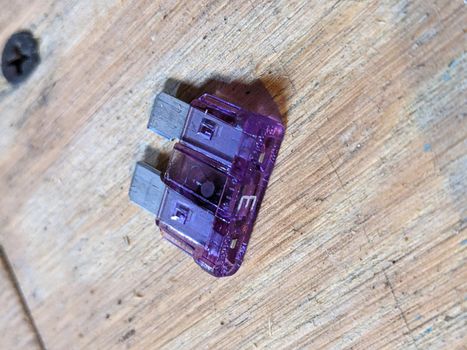 purple 5 amp fuse on flywood background