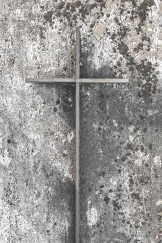 Iron christian cross on an old concrete wall