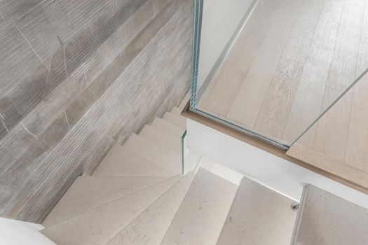 Grey microcement stairs with glass handrail. Stairs viewed from above. Modern design and innovative material. Glass railing.