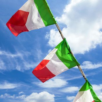 Italian flags on sky background. Small italian flags waving in the wind against blue sky.