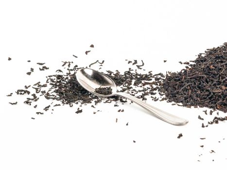 Spoon with leaves of tea on isolated white background.