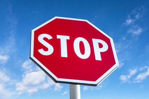 Roadside red stop sign on a cloudy background