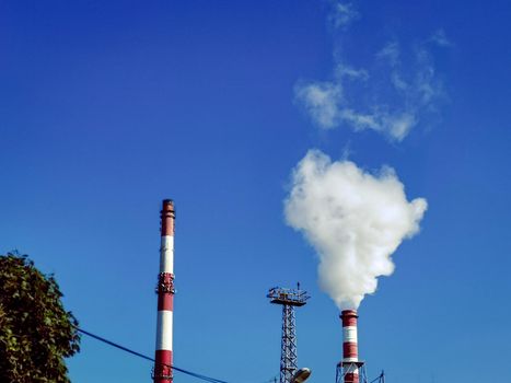 Clear sky over industrial plant pipes with smoking pipes