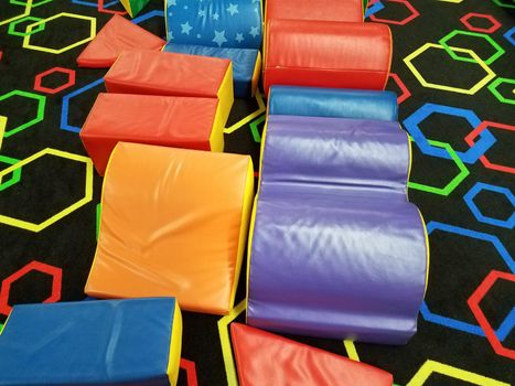 colorful soft foam blocks on black carpet with geometric shapes