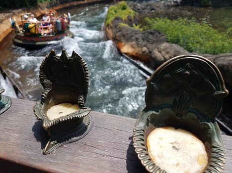 small candles on railing with river and rafters below