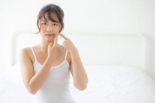 Beautiful portrait young asian woman with acne problem in the bedroom, trouble of beauty on face, zit treatment, asia girl is pimple having worry and displeased, skincare and healthy concept.