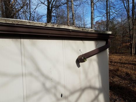 broken gutter downspout on storage shed in forest or woods