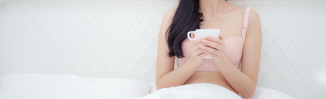 Beautiful young asian sexy woman in underwear drinking coffee in the morning on bed at bedroom, asia girl with seductive figure fit drinking beverage for relax, lifestyle concept, banner website.