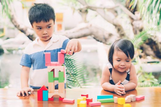 Asian boy and gril playing wooden block toy on table for creative and development with enjoy, happy child learn skill for activity puzzle and creativity for game on desk at home, education concept.