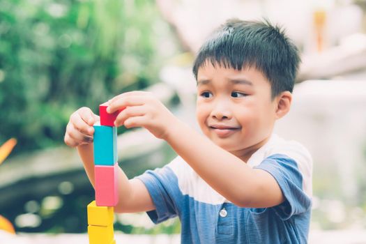 Asian young boy playing wooden block toy on table for creative and development with enjoy, happy child learn skill for activity puzzle and creativity for game on desk at home, education concept.