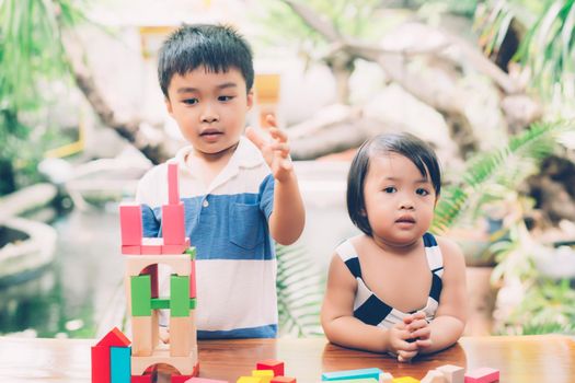 Asian boy and gril playing wooden block toy on table for creative and development with enjoy, happy child learn skill for activity puzzle and creativity for game on desk at home, education concept.