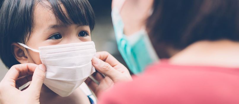 Mother take care daughter with face mask for protection disease flu or covid-19 outdoors, mom wearing on medical mask with child safety for protect outbreak of pandemic, banner website.