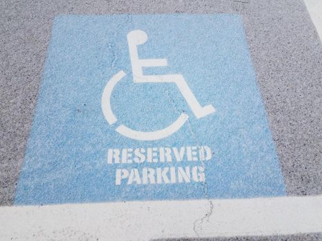 blue wheelchair reserved parking sign on black asphalt with white snow and ice
