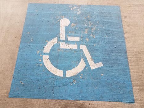 blue wheelchair or handicapped parking symbol on cement or pavement